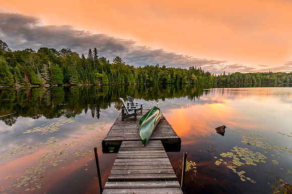 Green Canoe and Chairs on a Dock at Sunset