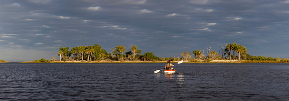Panorama of woman kayaking in the Gulf of Mexico with birds flyi